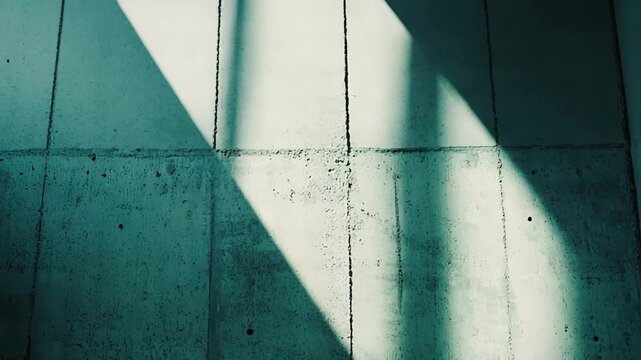 Concrete wall creating a textured background with natural diagonal light and deep shadows enhancing the rough surface, bringing an industrial and minimalist aesthetic