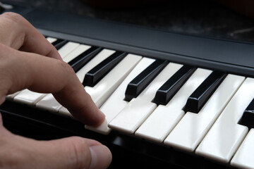 Fototapeta premium Close Up of Hand Playing Piano Keyboard, Music Practice and Learning Concept.