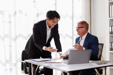 Fototapeta premium Two business people point to graphs and charts to analyze market data, balance sheet, account, net profit to plan new sales strategies to increase production capacity.
