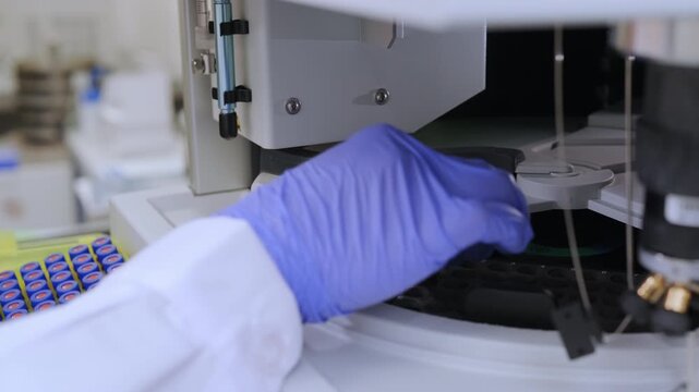Close up of woman placing sample vials in HPLC system. Pharmaceutical laboratory, chromatography analysis and scientific research concept.