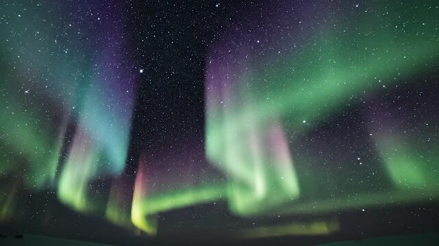 Vibrant green and purple celestial light display illuminates the dark night sky