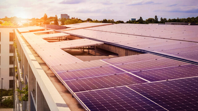 Solar Panels of Modern Apartment Building Roof. High rise Residential Apartment Complex with Solar Photovoltaic Panel on Roof in Cityscape Background with Sunset.