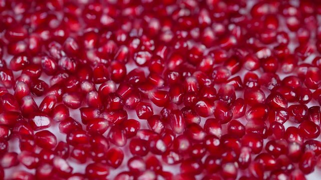 Shiny pomegranate seed closeup. Detailed view of glossy pomegranate crystals. Macro photograph capturing sparkling red pomegranate seeds arranged in natural pattern