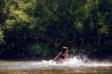 Fototapeta premium Happy family time outdoors. Playful teenager girl swimming and splashing in the river. Happy carefree moments. A fun time of discovery, play, and adventure. Having fun in travel, vacations. Humor