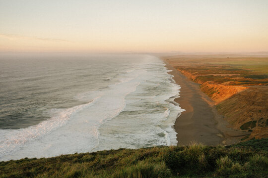 Aerial view of rugged coastline with waves at sunset