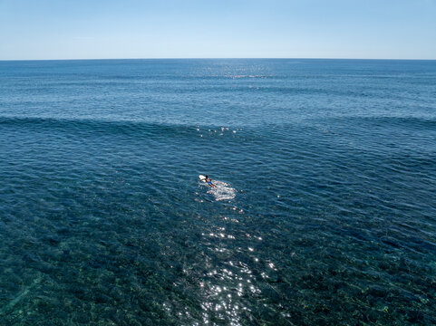Aerial view surfer paddling to catch waves Kawaikui Beach Hawaii