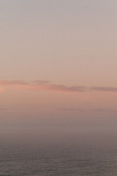 Minimal seascape with soft pink sky above calm ocean