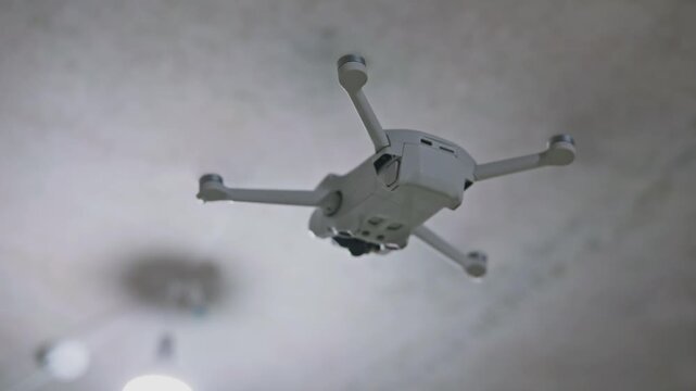 Close-up view of a drone hovering under the ceiling inside a building. Indoor aerial flight, stabilized quadcopter and precise position control in confined space. High quality 4k footage