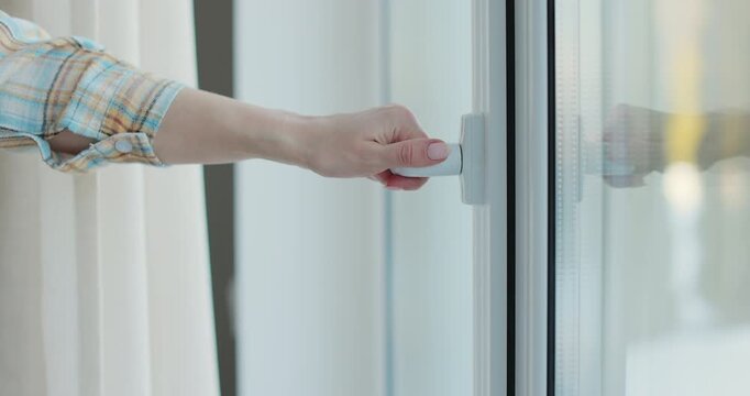 Close-up young woman opening window to refresh room.