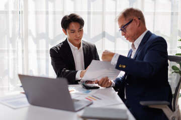 Fototapeta premium Two business people point to graphs and charts to analyze market data, balance sheet, account, net profit to plan new sales strategies to increase production capacity. 