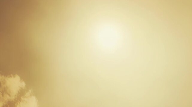 Golden light from a visible sun radiates across a soft sky with delicate clouds, creating a bright and warm atmospheric background for various design needs