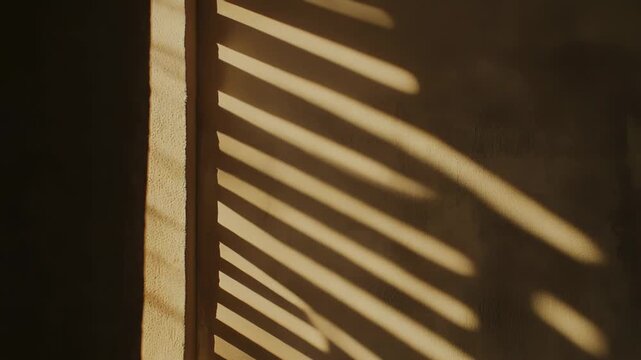 Sunlight casting strong parallel striped shadows on an indoor wall, bringing warmth and abstract patterns to a neutral textured surface, creating a visual interplay of light and shadow