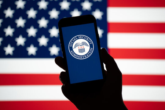 United States Social Security Administration SSA logo sign on smartphone, American flag in bg. Federal insurance program providing retirement, benefits on February 17, 2026 in Krakow, Poland.