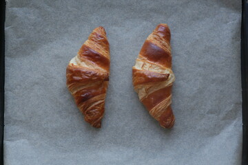 two butter croissants on parchment photographed from above