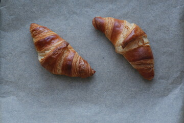 two butter croissants on parchment photographed from above