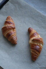 two butter croissants on parchment photographed from above