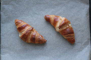 two butter croissants on parchment photographed from above
