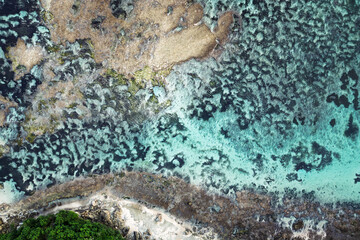 Obraz premium Aerial tropical shoreline with turquoise water over coral reef, organic patterns for nature background, summer travel and serenity.