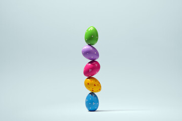 Stack of five polka dot Easter eggs stands upright on pale blue studio backdrop, clean spring concept with soft floor shadow. © SOLDATOOFF