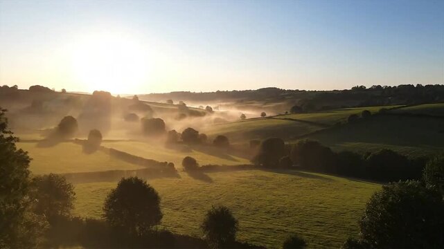 A serene sunrise over rolling hills and trees, misty atmosphere, video footage 16.mp4