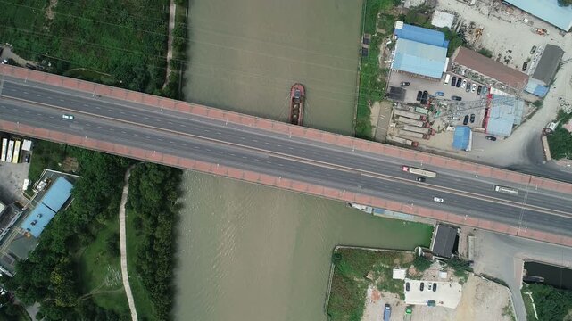 Overhead drone shot of cargo vessel crossing underneath a bridge while sailing through the Grand Canal in Suzhou, China