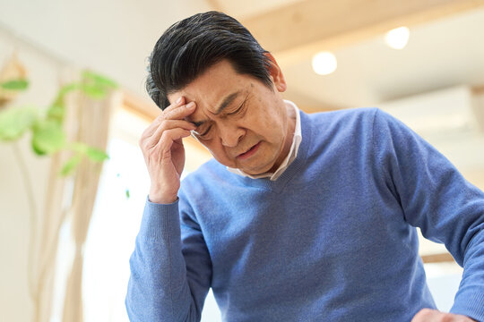 認知症で頭を抱えるアジア人シニア男性