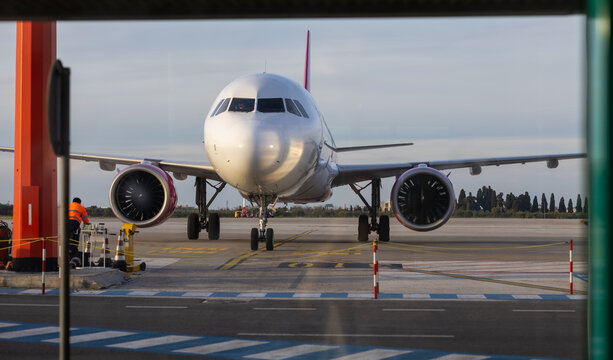 front view of a wizz air airbus a321neo parked on the airport apron with ground crew during golden hour, commercial aviation industry and air travel concept