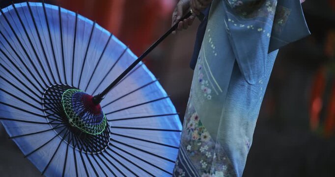 Closeup on woman in kimono dress holding her open umbrella near her feet