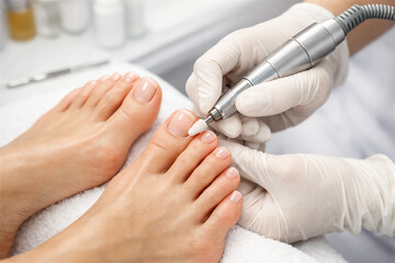 Fototapeta premium professional pedicurist shaping client's toenails and cuticles using an electric nail file focusing on foot hygiene and aesthetic beauty treatment at a modern salon or podiatry clinic