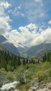 Time lapse of clouds moving over mountains. Meadow in mountains in front alps mountains. Fast-moving clouds revealing an alpine valley landscape with forests and mountain scenery. Dynamic atmospheric 