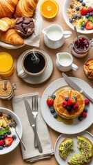 Overhead view of a colorful breakfast spread with waffles croissants fruit and coffee.