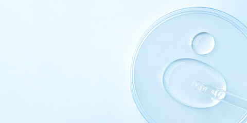 Drop of cosmetics and a pipette on a blue background. A product for skin, face or hair care.