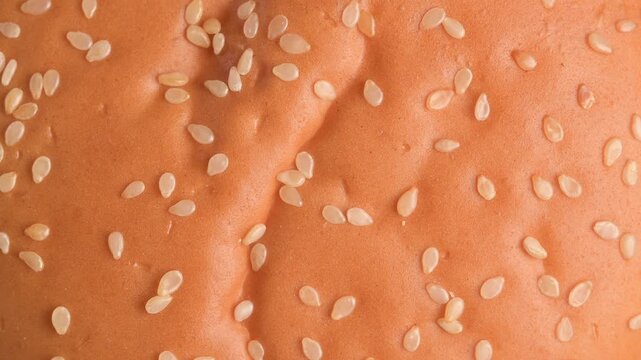 Macro rotating video of a hamburger bun topped with sesame seeds, highlighting texture, surface detail, and bakery freshness. The slow rotation emphasizes food presentation and appetizing qualities