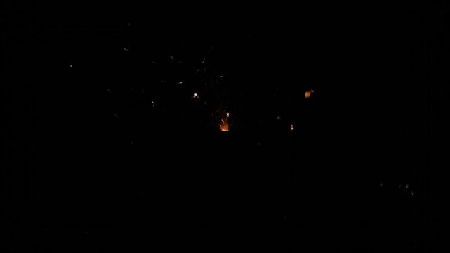 Golden sparks exploding outwards on a dark black background