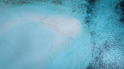 Aerial view with crystal clear with summer lagoon ripples in the sand at low tide on a beach with sandbar and blue sea in Raja ampat,indonesia