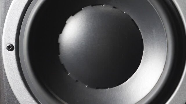 Close up of moving professional sub-woofer on recording studio. A black round audio speaker pulsating and vibrating from sound on low frequency. Work of high fidelity loudspeaker membrane. Slow motion