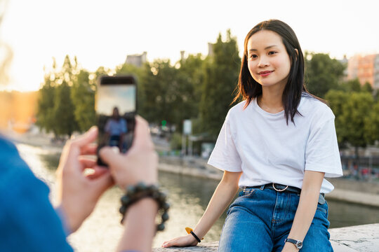 France, Paris, man taking a picture of his girlfriend at river Seine at sunset