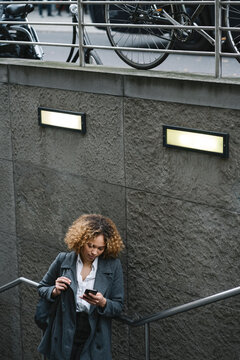 Woman using smartphone at the entrance of a subway station, Berlin, Germany