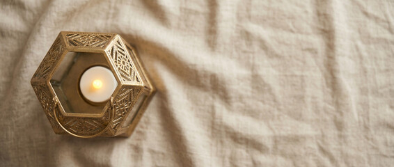 Decorative lantern with candle on fabric background concept of ramadan  
