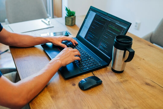 Male web designer programming through on laptop at desk in office