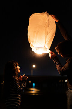 Father and daughter preparing a sky lantern at night