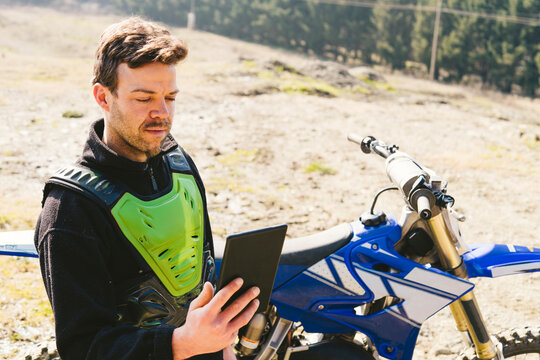 Portrait of motocross driver looking at tablet