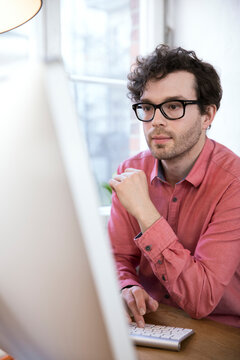 Confident man in office looking at computer screen
