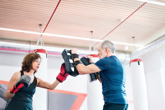 Fit senior woman boxing with her coach