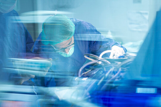 Focused male orthopedic surgeon operating with coworker in ICU