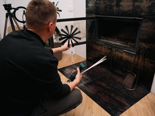 Man preparing to clean a modern indoor fireplace with a professional chimney brush.
