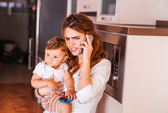 Annoyed mother with her son talking on the phone at home