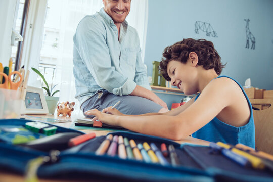 Father helping boy doing his schoolwork at home