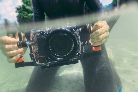 Man holding underwater DSLR camera case in a lake