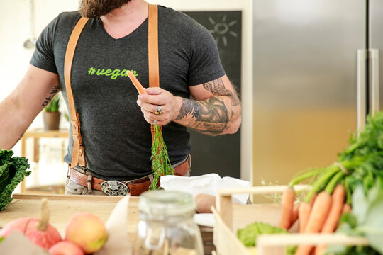 Vegan man holding carrot in his kitchen